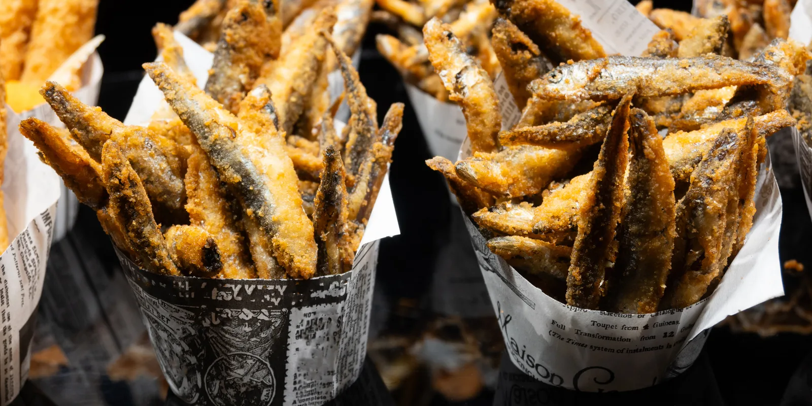 Paper cone of mixed fried fish on the counter of a freiduría in Seville