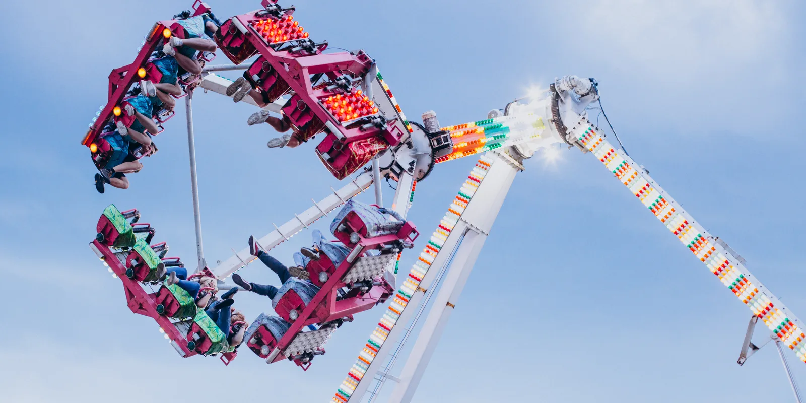 A spinning amusement park ride full of people against the sky