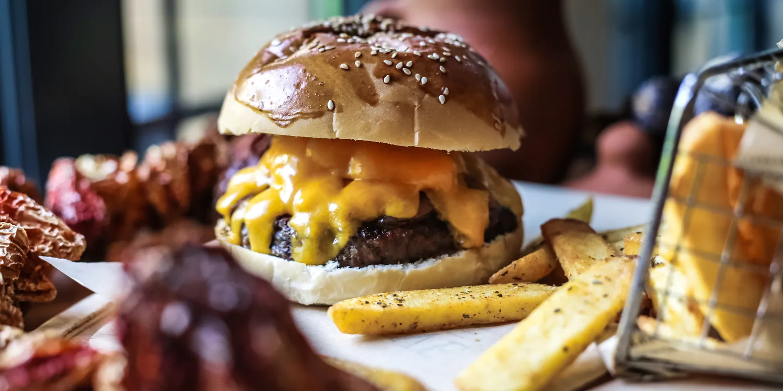 Hamburguesa doble con queso fundido y patatas fritas caseras sobre la barra de una hamburguesería de Sevilla