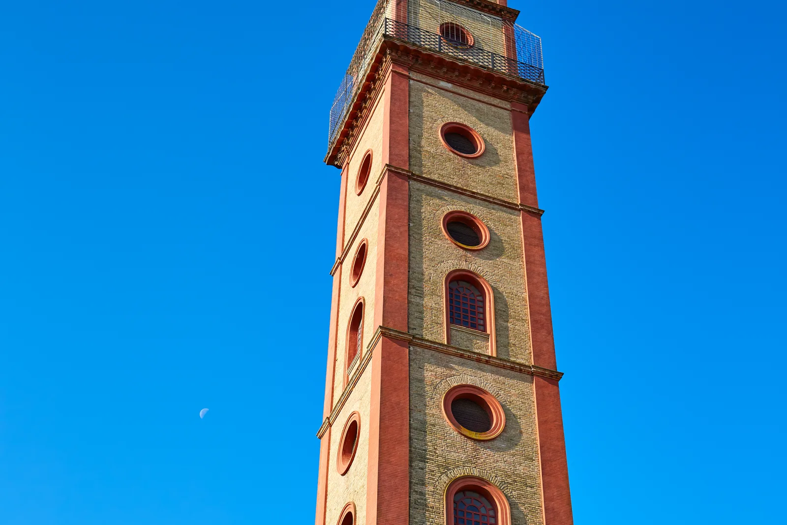 Torre alta de ladrillo con óculos redondos contra un cielo azul