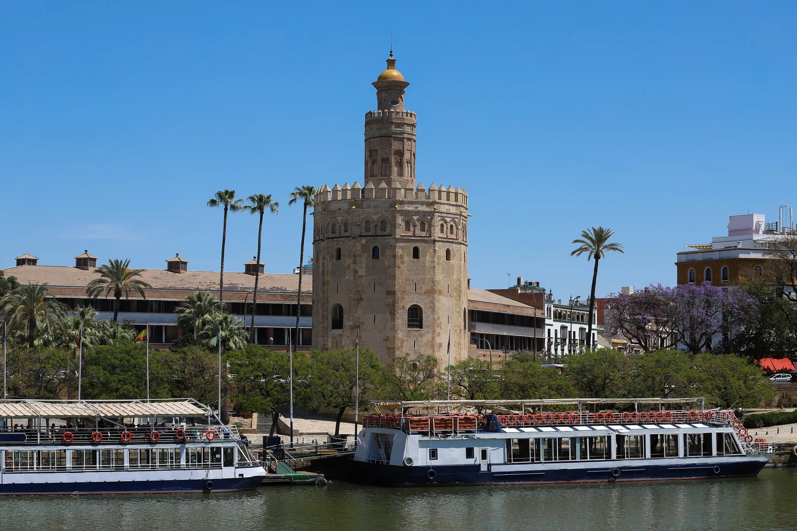 Torre militar dodecagonal de piedra junto al río con barcos de paseo amarrados